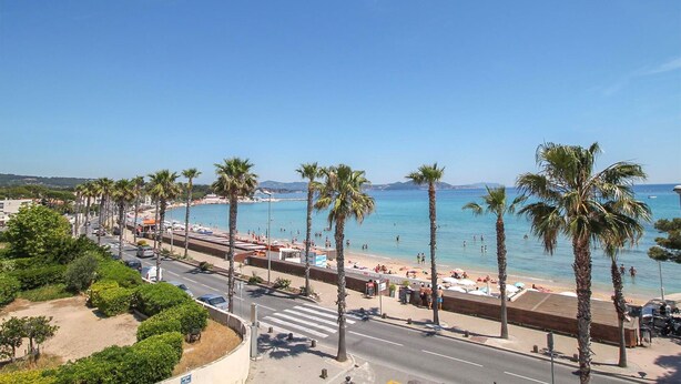 Eine Küstenstraße mit Palmen, einem Strand und blauem Himmel.