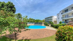 Ein Wohngebäude mit Schwimmbad, umgeben von Grünflächen und blauem Himmel.