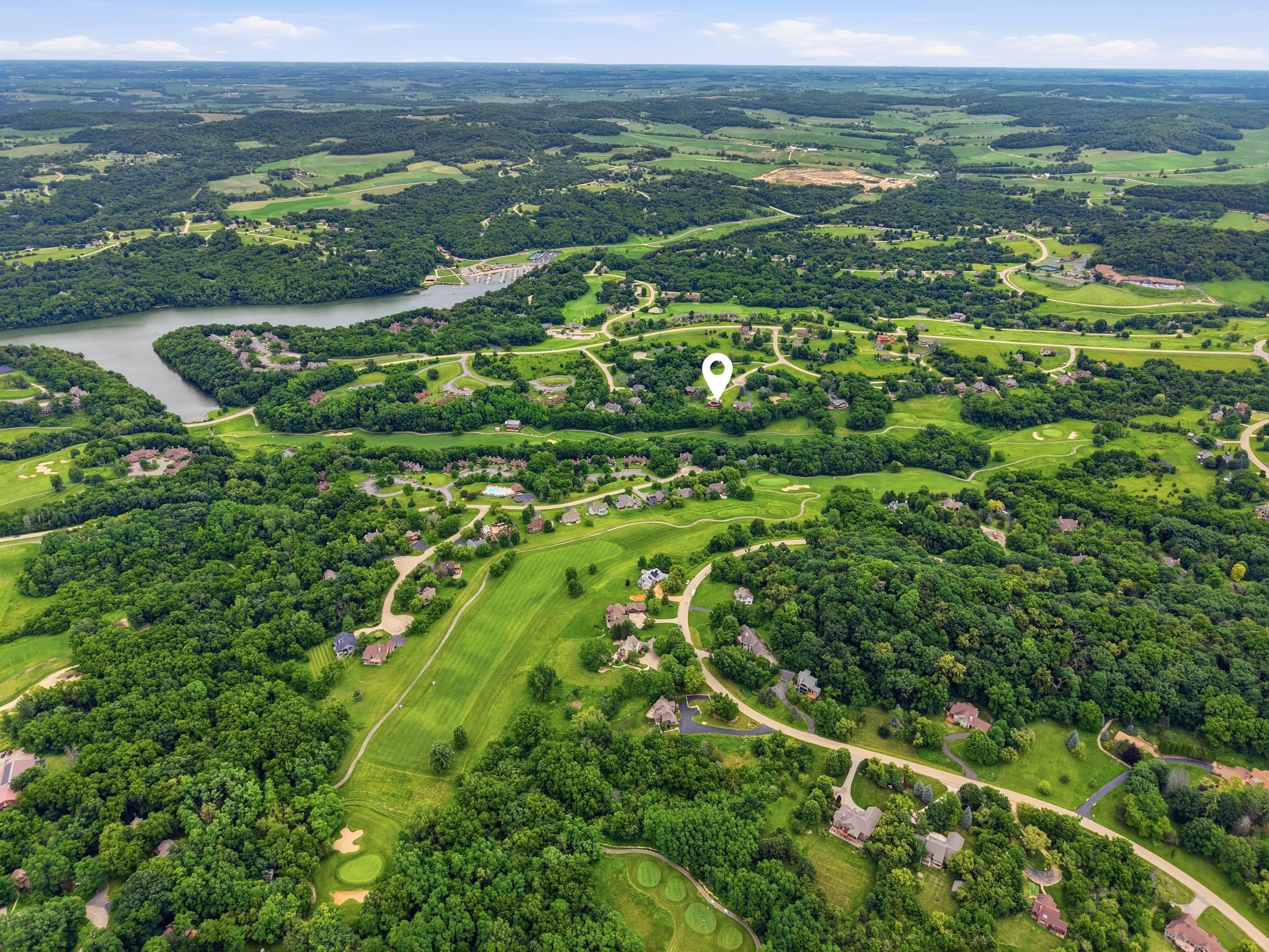 An aerial view of a golf course with a lake, surrounded by residential areas and greenery.