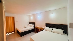 A hotel room with two beds, a wooden nightstand, a white curtain, and a light fixture on the ceiling. - The Victoria Hill Cottage  (Digana)