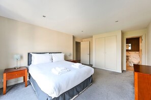 Ein Hotelzimmer mit Bett, Nachttischen, einem Kleiderschrank und einem durch eine offene Tür einsehbarer Badezimmer.
