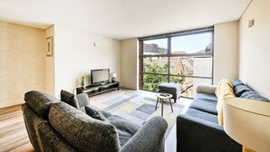 Una sala de estar moderna con un ventanal grande, un televisor de pantalla plana y un sofá.