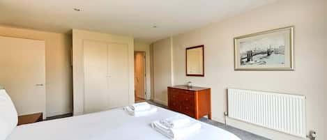 A hotel room with a bed, a dresser, a radiator, and a framed picture on the wall.