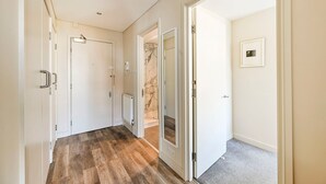 Un pasillo con puertas blancas, un radiador y una pared de mármol.