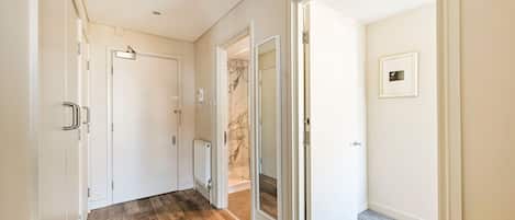 A hallway with white doors, a radiator, and a marble wall.