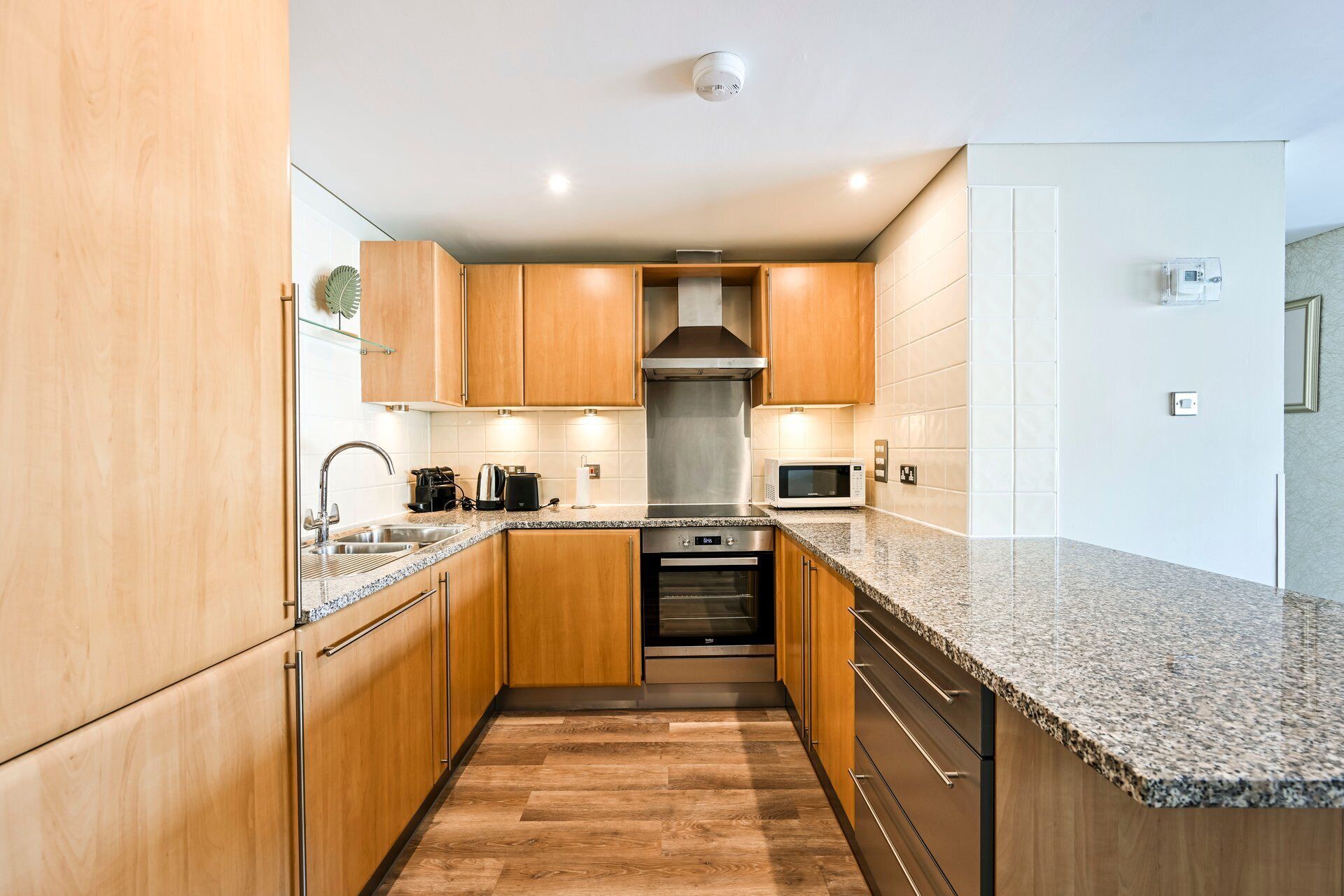Une cuisine moderne avec des meubles en bois, des appareils en acier inoxydable et un plan de travail en granit.
