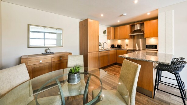 Una cocina moderna con armarios de madera, una campana extractora de acero inoxidable y una encimera de granito.