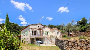 A two-story house with a stone wall, a balcony, and a stone oven. - 3 bedroom pet friendly home in Tauriers (Tauriers)