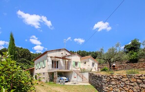 A two-story house with a stone wall, a balcony, and a stone oven. - 3 bedroom pet friendly home in Tauriers (Tauriers)