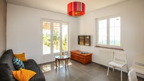 A living room with a sofa, a small table, a radiator, and a window with a view. - 3 bedroom pet friendly home in Tauriers (Tauriers)