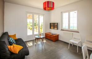 A living room with a sofa, a small table, a radiator, and a window with a view. - 3 bedroom pet friendly home in Tauriers (Tauriers)
