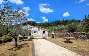 A stone house with a tiled roof, a gravel driveway, and a stone wall. - 3 bedroom pet friendly home in Tauriers (Tauriers)