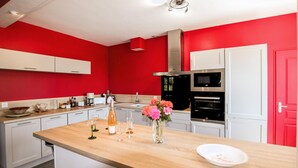 A modern kitchen with red walls, white cabinets, a wooden countertop, and a stainless steel range hood. - 3 bedroom pet friendly home in Tauriers (Tauriers)