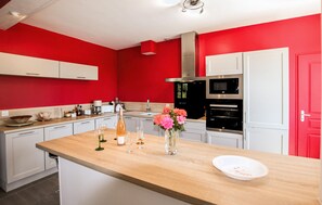 A modern kitchen with red walls, white cabinets, a wooden countertop, and a stainless steel range hood. - 3 bedroom pet friendly home in Tauriers (Tauriers)