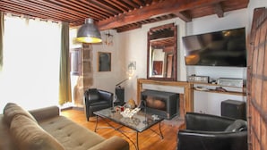 A living room with a sofa, two armchairs, a glass coffee table, a fireplace, a television, and a sound system. - Cozy home in Pelussin with WiFi (Pelussin)
