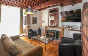 Ein Wohnzimmer mit einer Couch, zwei Sesseln, einem Glastisch, einem Kamin, einem Fernseher und einer Stereoanlage.