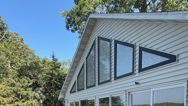 Uma casa moderna com varanda, móveis de exterior e grandes janelas com vista para a água.
