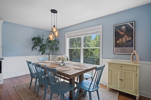 Un comedor con una mesa de madera, sillas azules y lámparas colgantes.