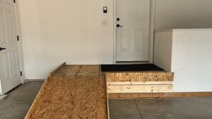 Quarto com piso de madeira, porta branca e chão de concreto.
