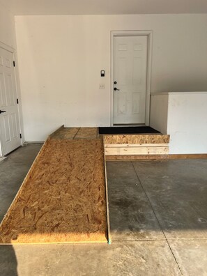 A room with a wooden floor, a white door, and a concrete floor.