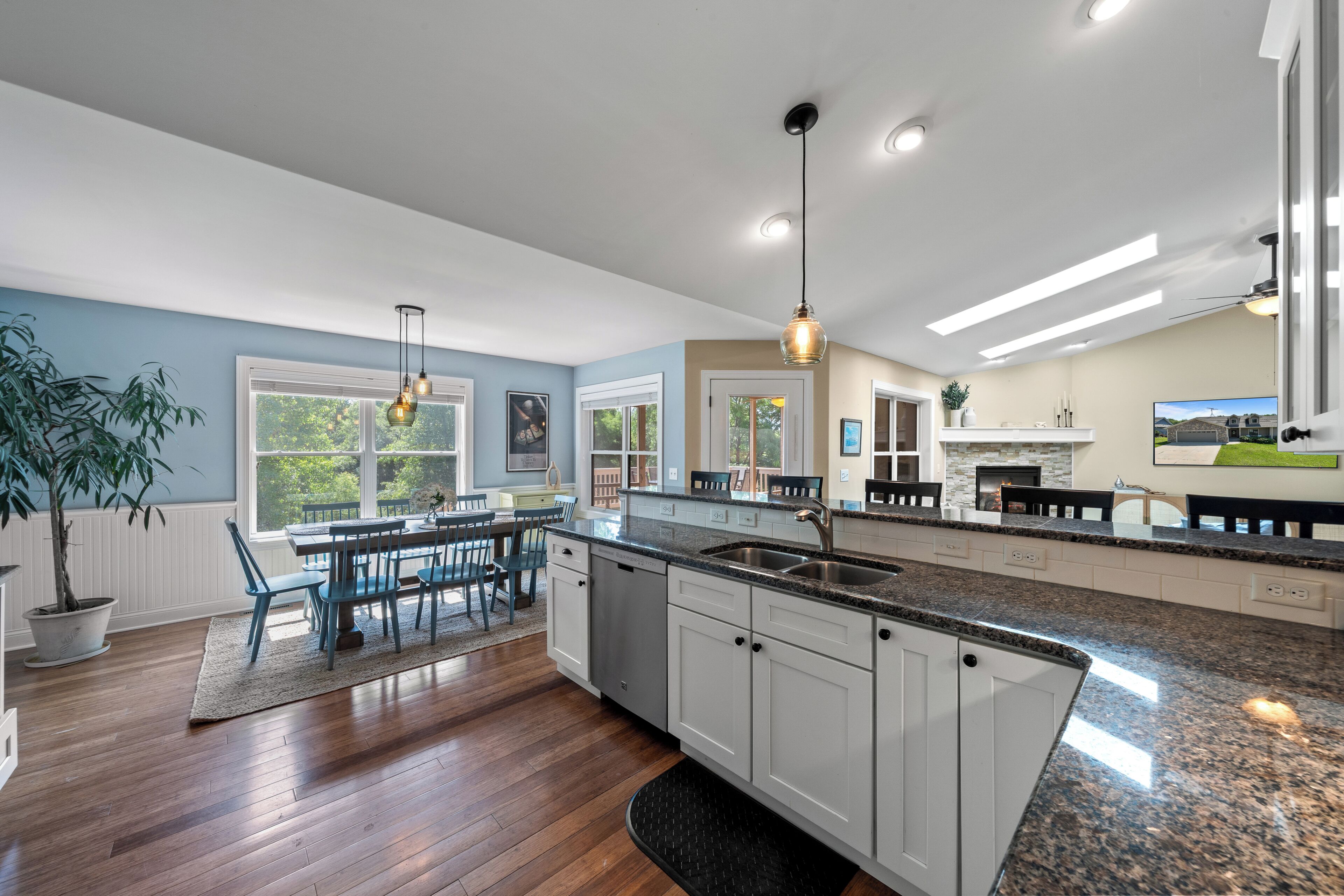 A modern kitchen with granite countertops, white cabinetry, and a dining area with a table and chairs.