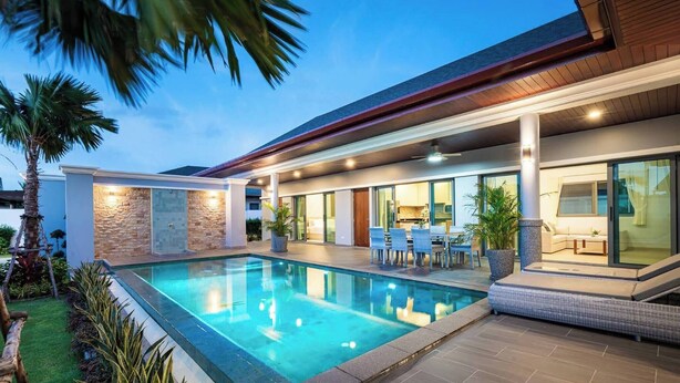 Ein modernes Haus mit Swimmingpool, Sitzgelegenheit im Freien und einer Terrassenfläche.