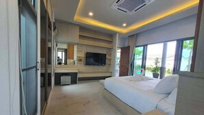 Ein modernes Hotelzimmer mit einem großen Bett, einem Fernseher, einer Minibar und Blick ins Freie.
