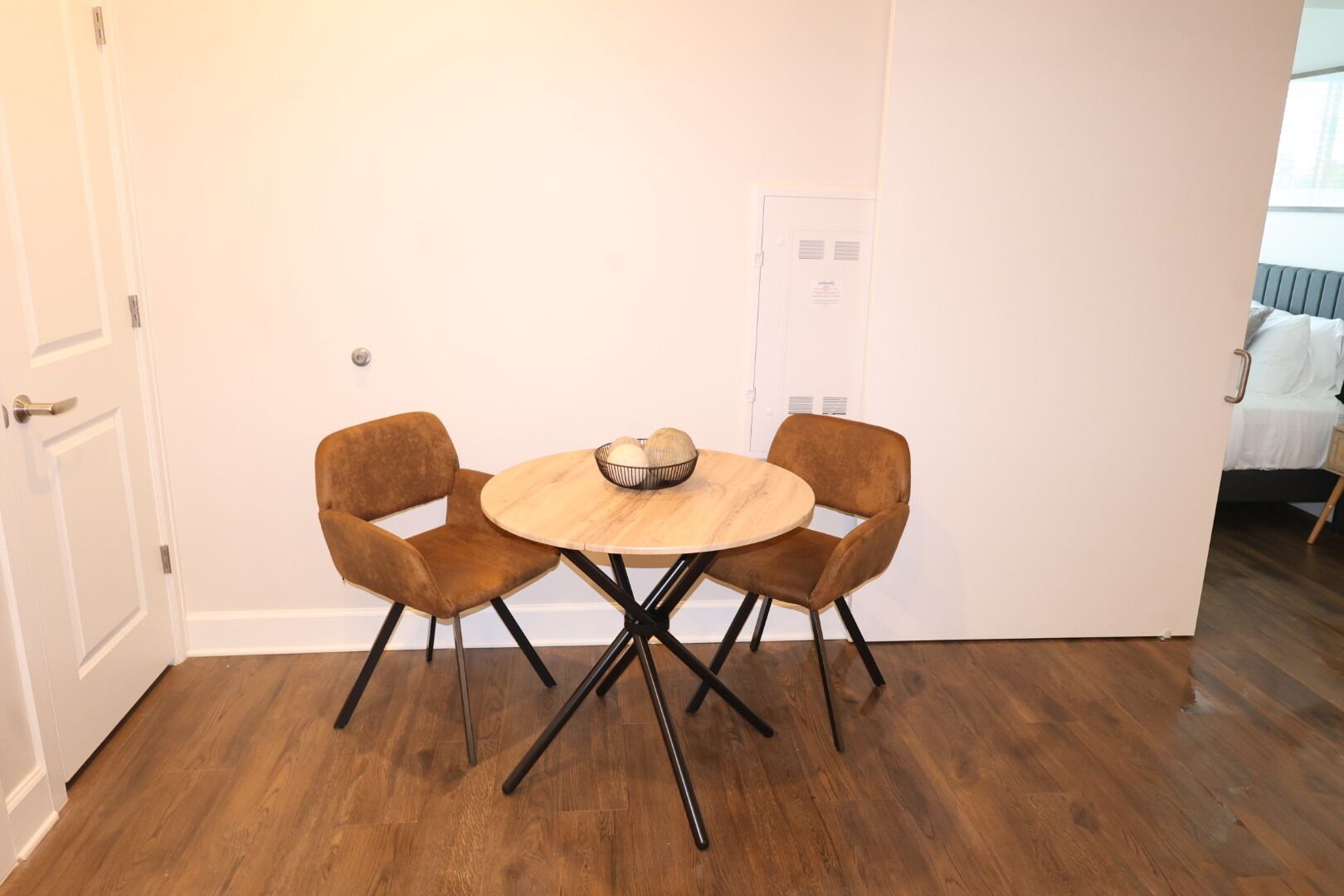 Un comedor con una mesa redonda de madera y dos sillas tapizadas en marrón con patas de metal negro.