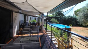 Un espacio al aire libre techado con piscina, asientos y vista al jardín trasero.