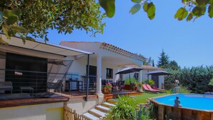Zona junto a la piscina con piscina, sillones de descanso y una pérgola.