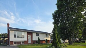 Ein einstöckiges Haus mit Veranda, Garage und einem gepflegten Rasen.