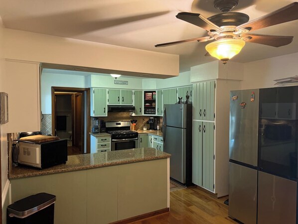 A kitchen with a central island, a stove, a refrigerator, and a ceiling fan.