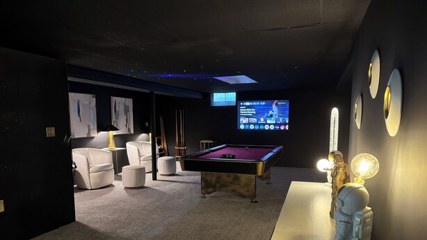Une pièce comprenant une table de billard, un canapé, un téléviseur et une figurine décorative.