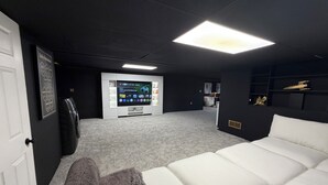 Une salle de cinéma privée équipée d’un grand écran, d’un espace salon et d’un centre de divertissement.