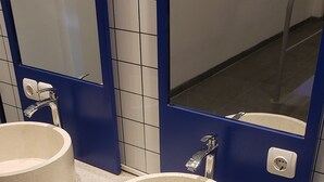 Un baño con dos lavamanos, un espejo y una pared de acento azul.