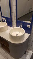Un baño con dos lavamanos, un espejo y una pared de acento azul.