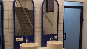 Baño público con dos lavamanos, espejos y una puerta azul.
