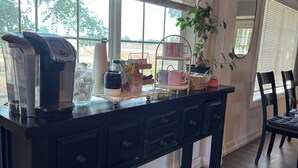 Un comptoir de cuisine avec une machine à café, une plante et un présentoir à tasses à plusieurs niveaux.