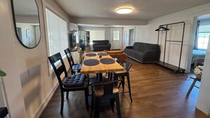 Un coin repas avec une table en bois, des chaises et un miroir au mur.