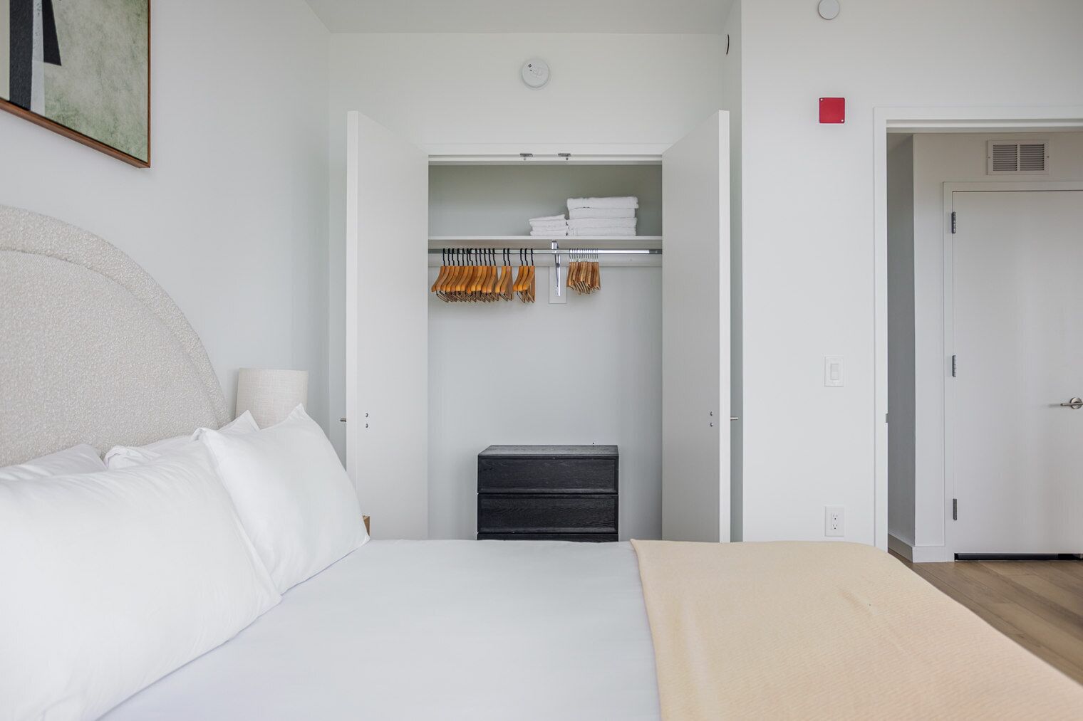 A bedroom with a bed, a wardrobe, and a small table.