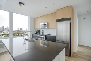 Uma cozinha moderna com uma ilha grande, eletrodomésticos de aço inoxidável e vista para a cidade.