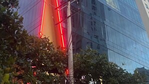 En høj, moderne glasbygning med et karakteristisk trekantet tag og en vertikal lysstribe ned ad midten.