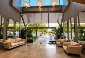A spacious lobby with a high ceiling, large windows, and a central seating area with sofas. - Wj Tower Santa Marta, near the historic center (Santa Marta)