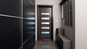 A hallway with a dark wooden door, a wall-mounted coat rack, and a small console table. - Puławska Urban Comfort Apartment (Warszawa)