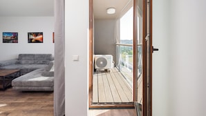 A modern living room with a sofa, a coffee table, and a balcony with a view. - Puławska Urban Comfort Apartment (Warszawa)