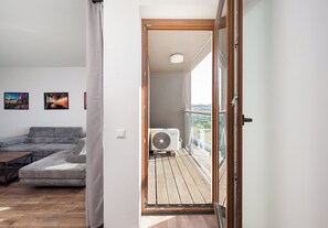 A modern living room with a sofa, a coffee table, and a balcony with a view. - Puławska Urban Comfort Apartment (Warszawa)