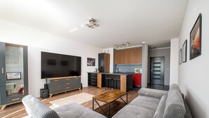 A modern living room with a grey sofa, wooden coffee table, and a flat-screen TV. - Puławska Urban Comfort Apartment (Warszawa)