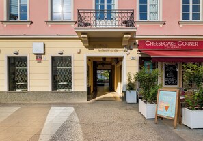 En bygning med en rød markise med påskriften 'Cheesecake Corner' og et skilt med et hjerte og et iscreme-symbol.