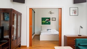 A bedroom with a bed, a desk, a cabinet, and a television. - Nowy Świat Sunny Side Apartment (Warszawa)