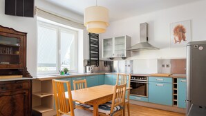 A modern kitchen with a dining table, chairs, and a refrigerator. - Nowy Świat Sunny Side Apartment (Warszawa)